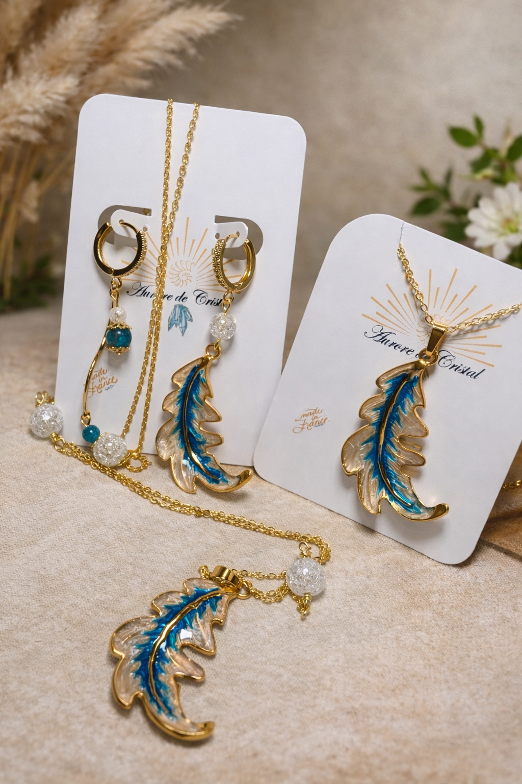 Parure Feuille d’Aurore avec boucles d’oreilles asymétriques – une feuille émaillée nacrée et bleue, l’autre avec perles de cristal de roche craquelé et apatite, et sautoir assorti avec pendentif feuille et perles de cristal de roche
