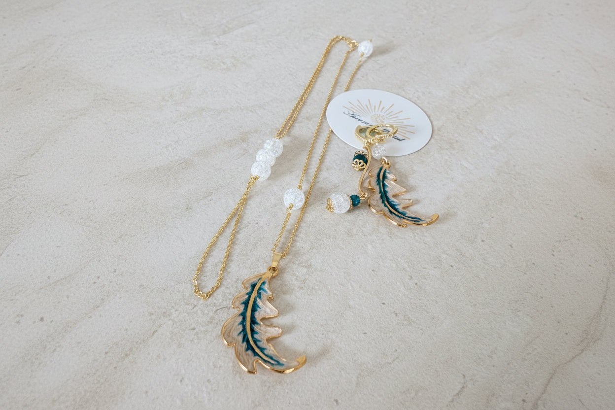 Parure Feuille d’Aurore avec boucles d’oreilles asymétriques – une feuille émaillée nacrée et bleue, l’autre avec perles de cristal de roche craquelé et apatite, et sautoir assorti avec pendentif feuille et perles de cristal de roche
